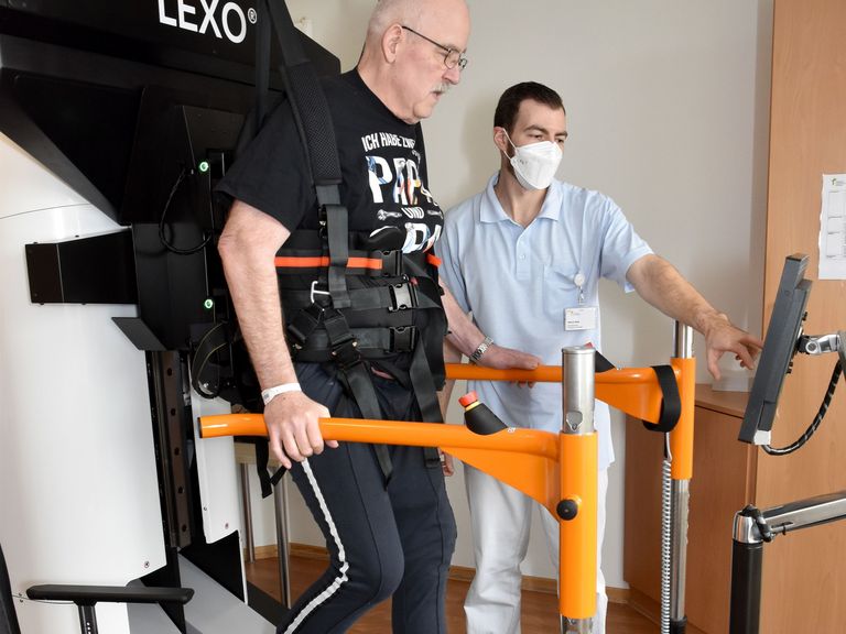 Patient auf Gangtrainer in Begleitung eines Physiotherapeuten - Interdisziplinäres Therapiezentrum - Neurologie - Albertinen Krankenhaus Hamburg